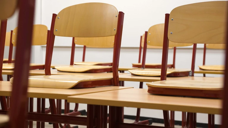 Schulreinigung in Feucht – Symbolfoto: Leerer Klassenraum mit Holztischen und Stühlen.